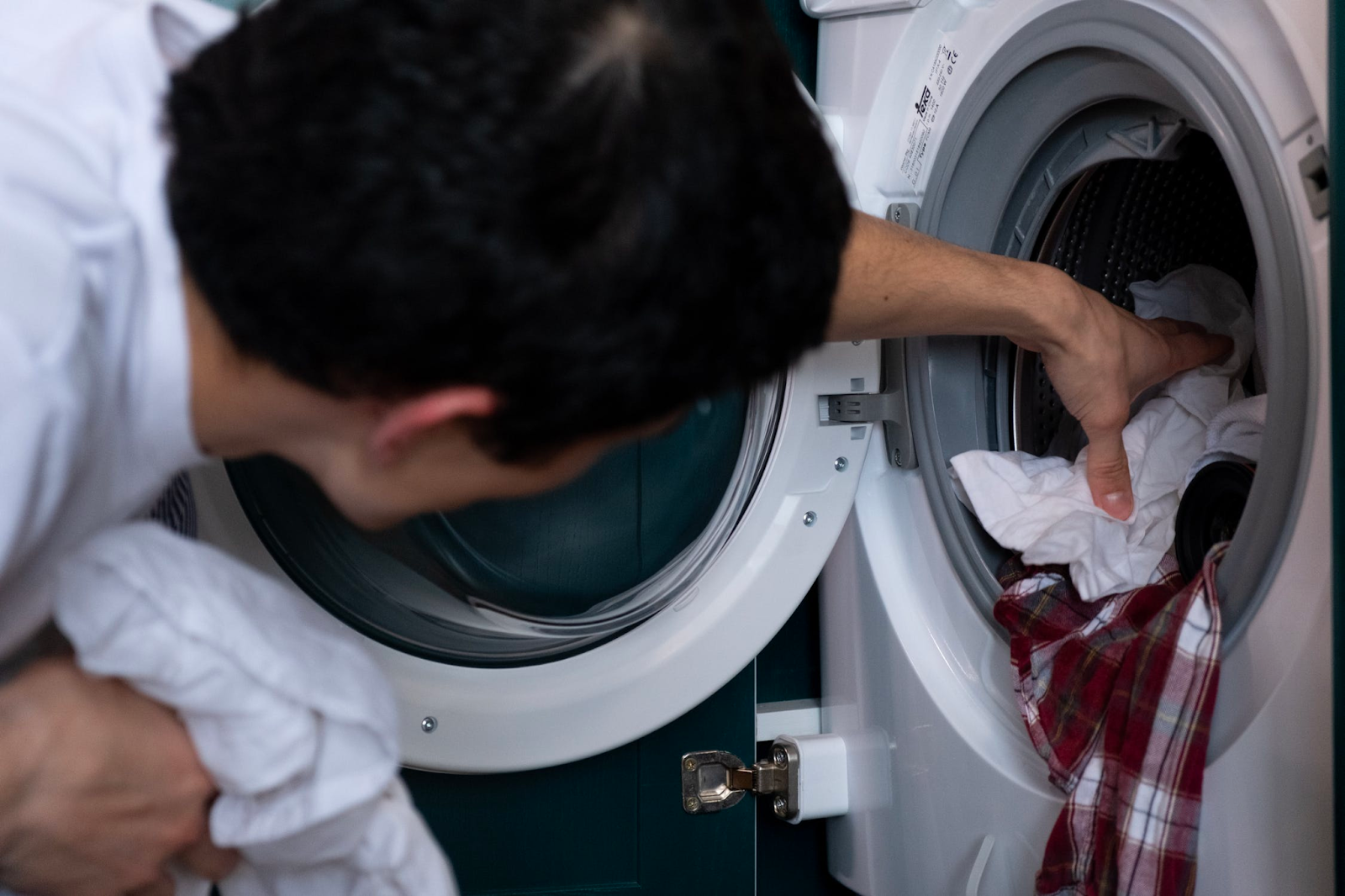 Man vult wasmachine met vuile was | Welhof NL